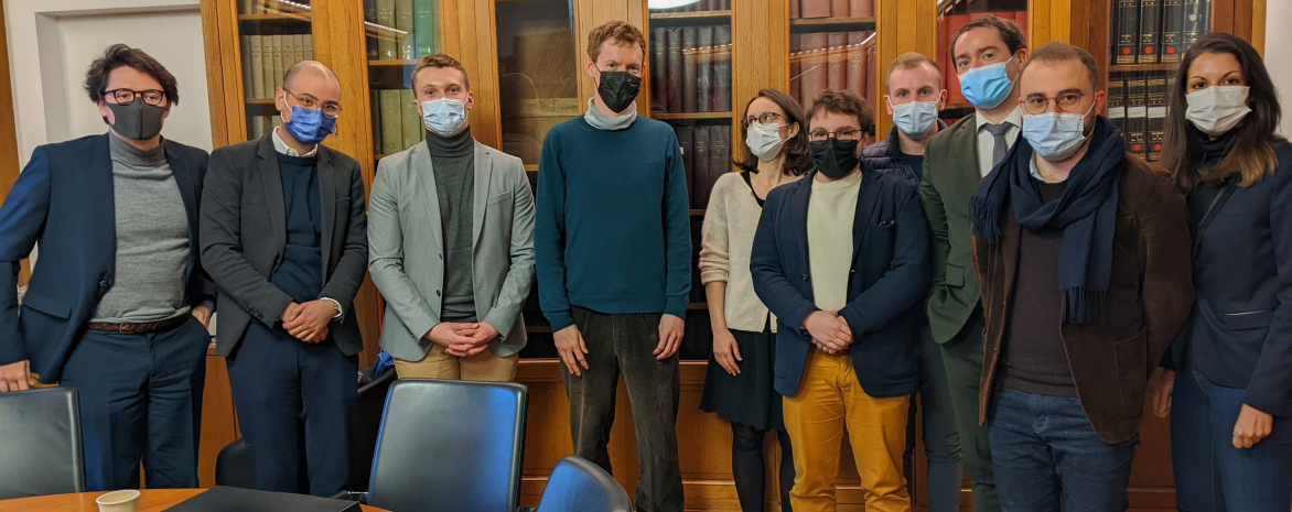 Le Professeur Ben McFarlane, des docteurs et des doctorants dans l'IRDA face à une vitrine remplie d'ouvrages